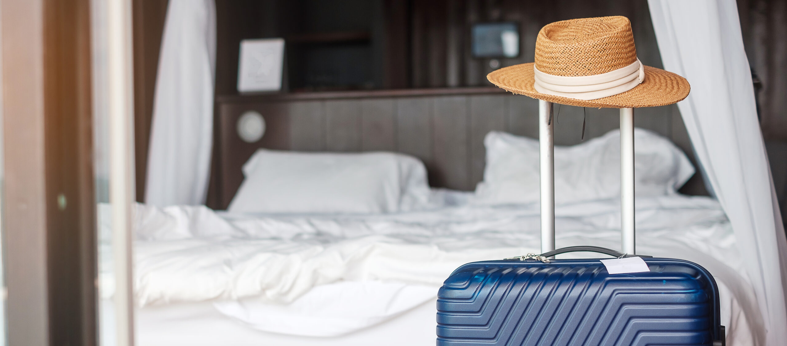 Blue Luggage with hat in modern hotel room after door opening.